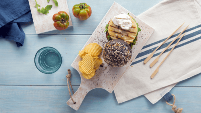 Burger di pesce con pane nero, rucola, stracciatella e pomodori